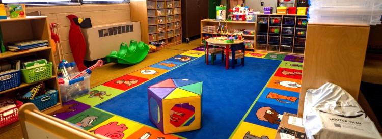 A colorful classroom with toys and books scattered on the floor, creating a playful learning environment.