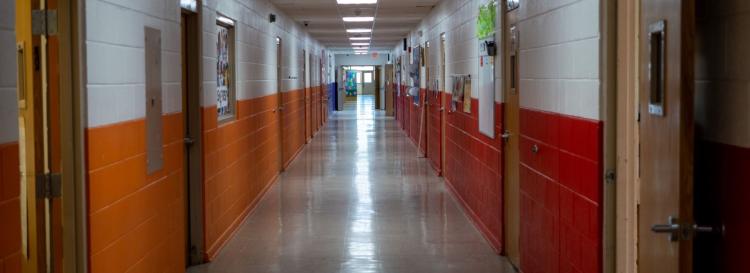 Looking down the school hallway featuring vibrant orange and white walls, creating a bright and inviting atmosphere.