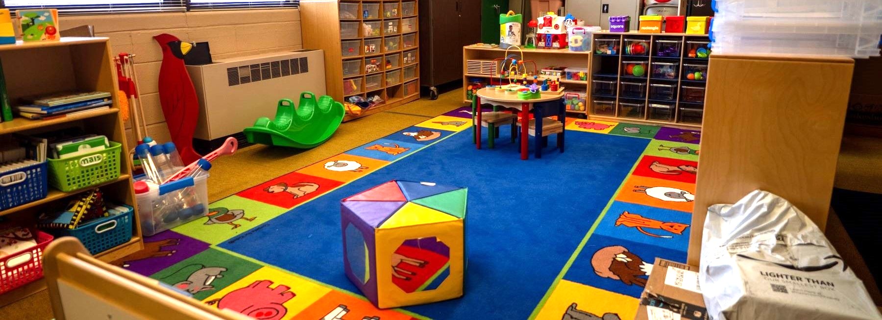 A colorful classroom with toys and books scattered on the floor, creating a playful learning environment.