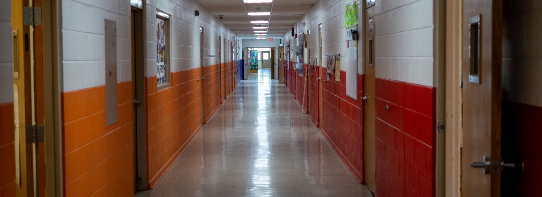 Looking down the school hallway featuring vibrant orange and white walls, creating a bright and inviting atmosphere.